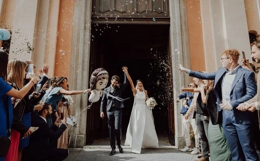 Coppia di sposi che esce dalla chiesa mentre gli invitati lanciano loro il riso, Fotografo di Matrimoni a Cuneo, matrimonio a Savigliano