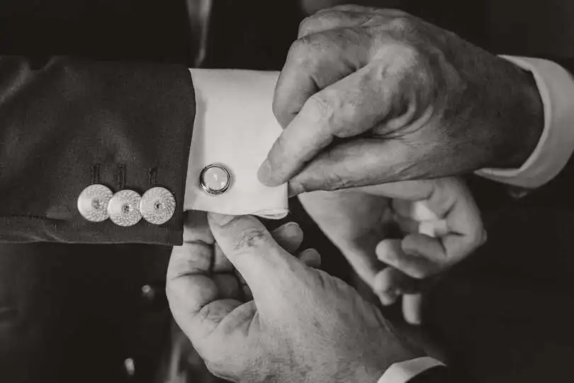 Dettaglio delle mani del papà che abbottona i gemelli allo sposo, Bianco e nero, Matrimonio a Pianfei, Fotografo di matrimoni a Cuneo